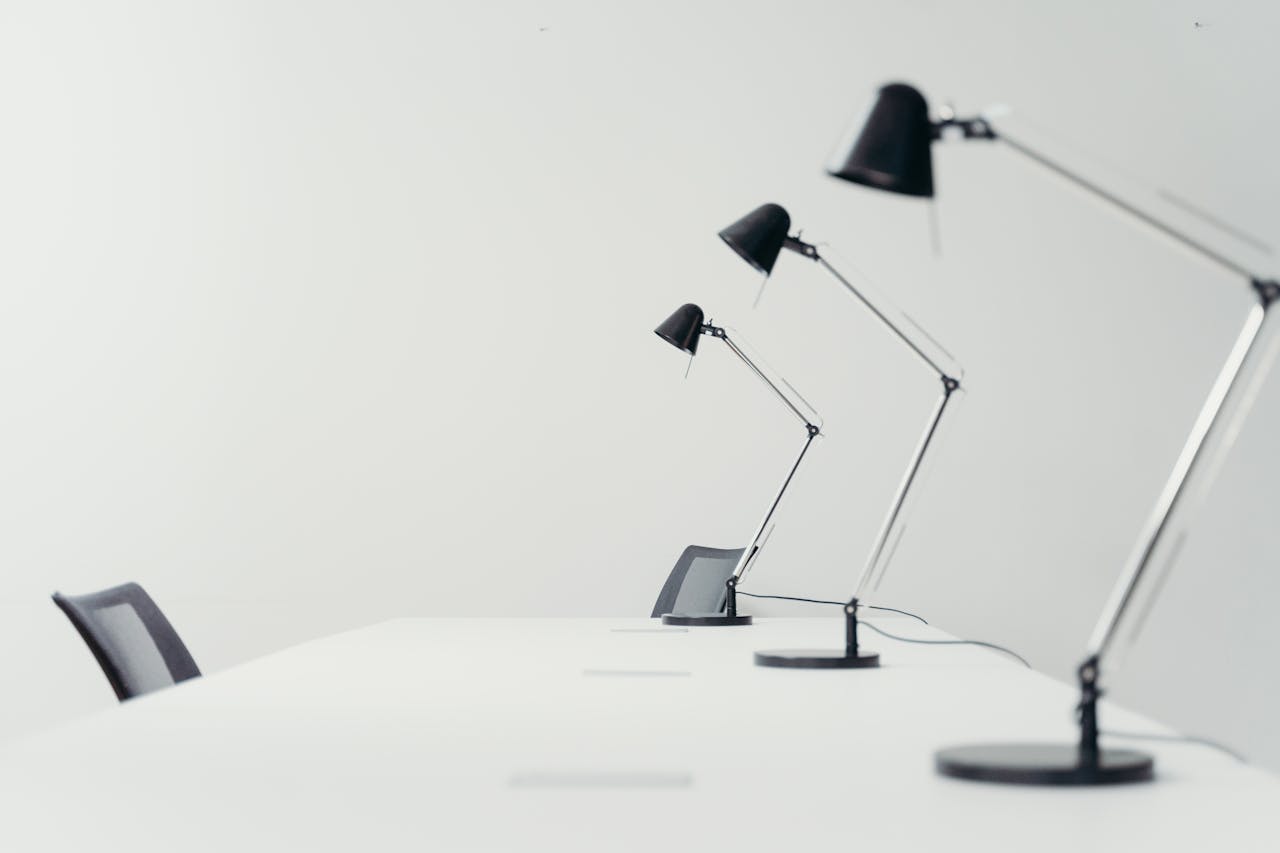 Sleek white office setting with modern black desk lamps and chairs, showcasing minimalism.